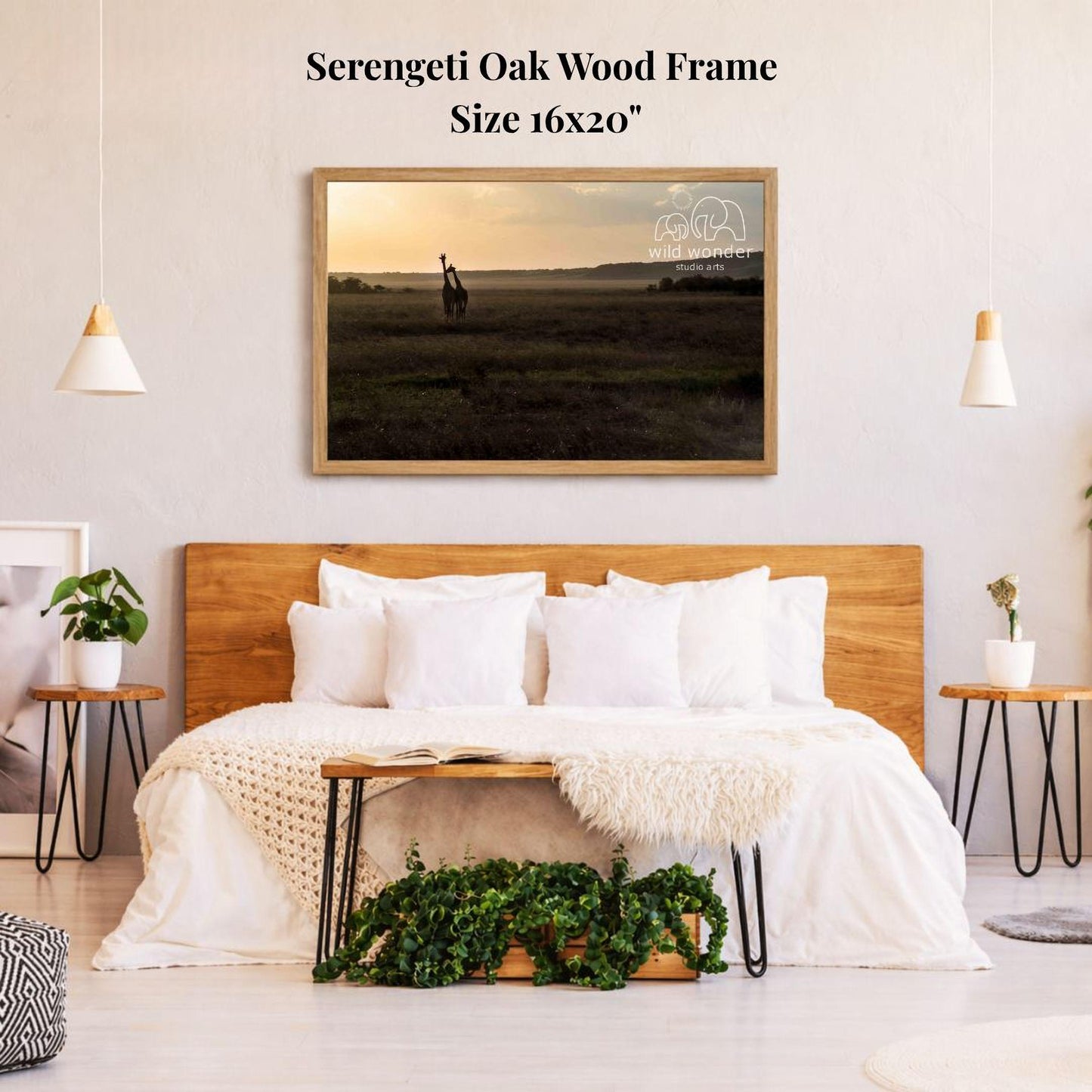 a serene bedroom scene with a large wooden headboard, a white bedspread, and a framed photograph of a giraffe in a field. The photograph is hanging on the wall above the bed, which is situated between two small side tables. The room has a minimalist and modern design, with a potted plant and a vase adding a touch of greenery to the space.