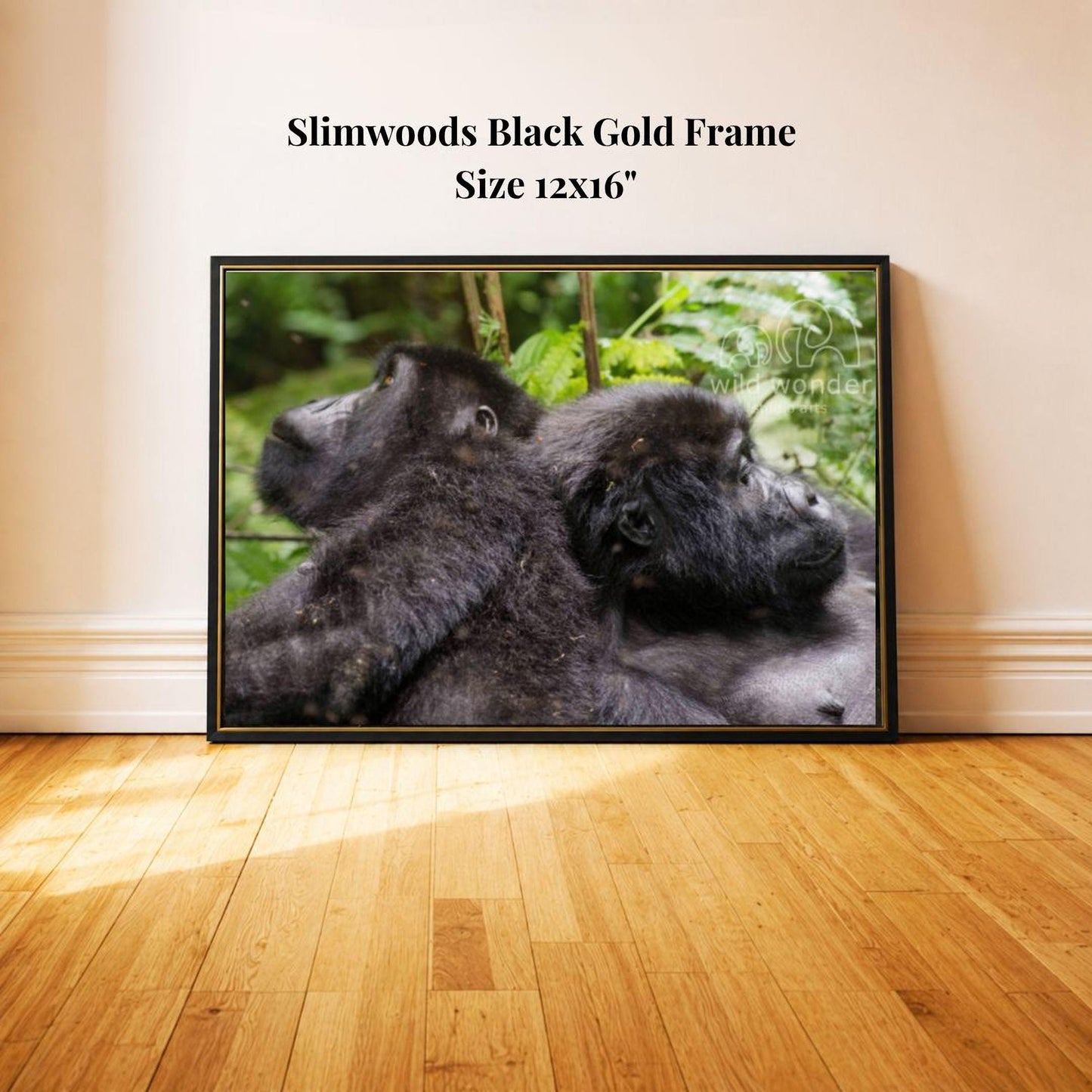 two black gorillas resting together on a wooden floor.
