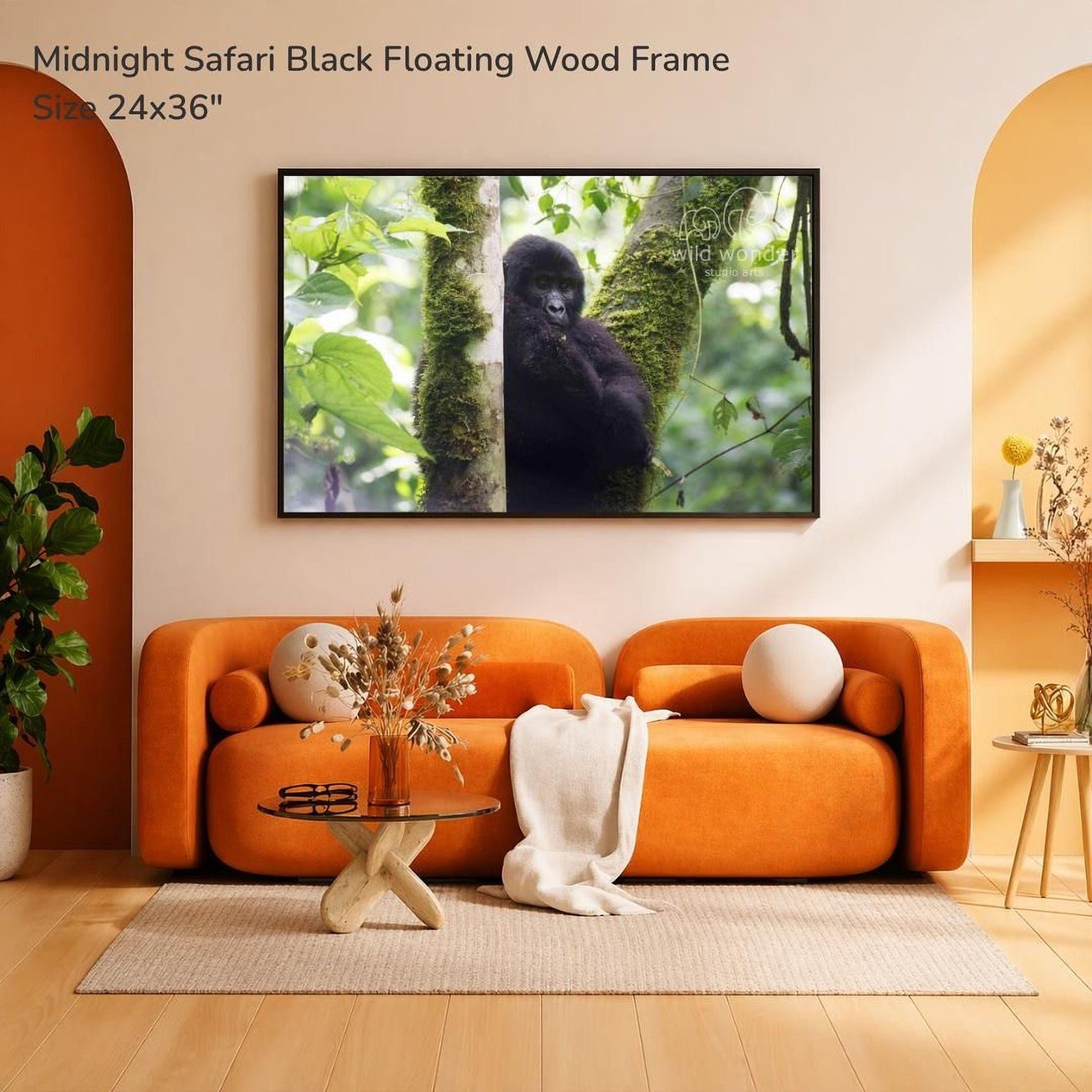 a large black floating wood frame with a photograph of a gorilla hanging on it, mounted on a wall above an orange sofa in a living room setting.
