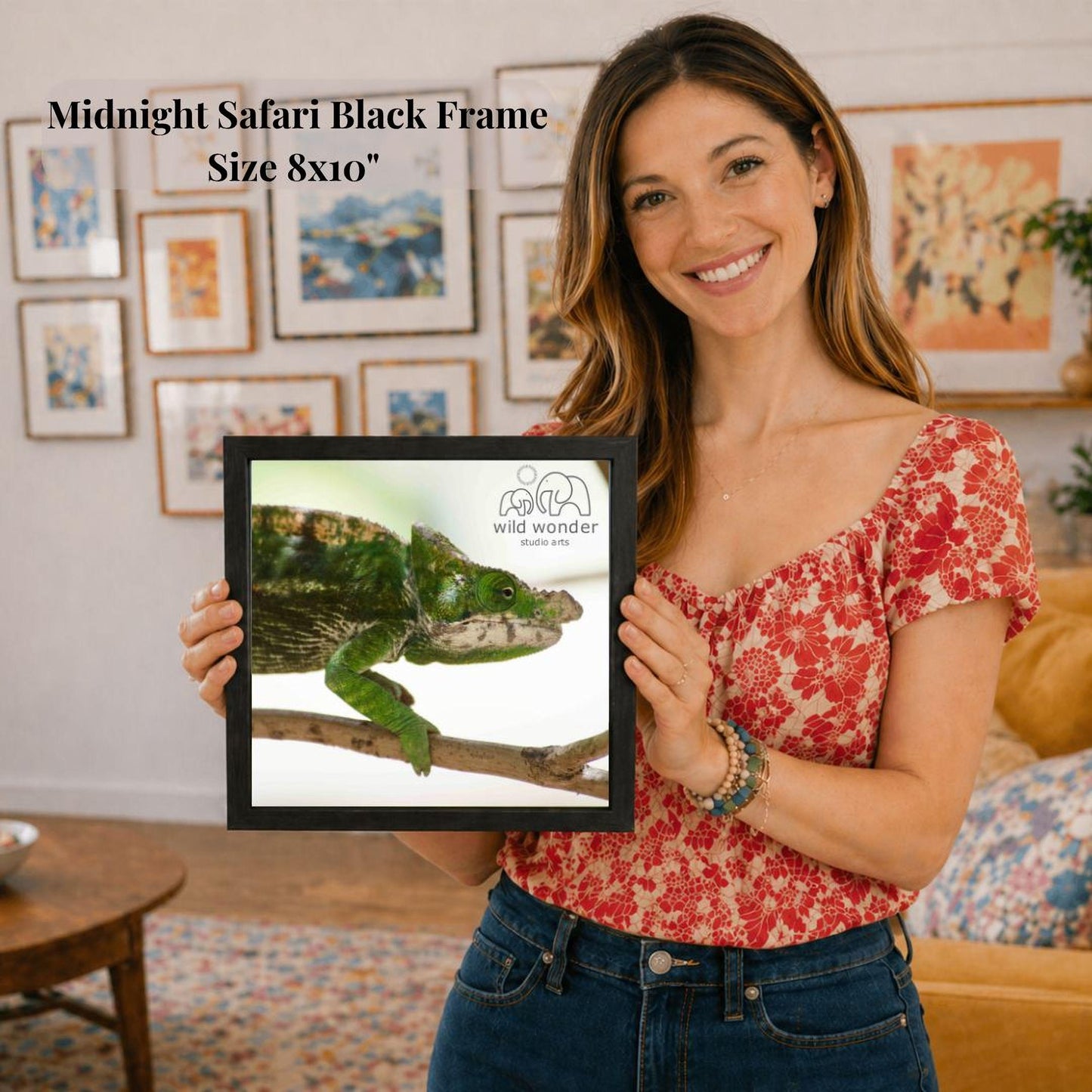 A woman is holding a framed picture of a chameleon in a living room.