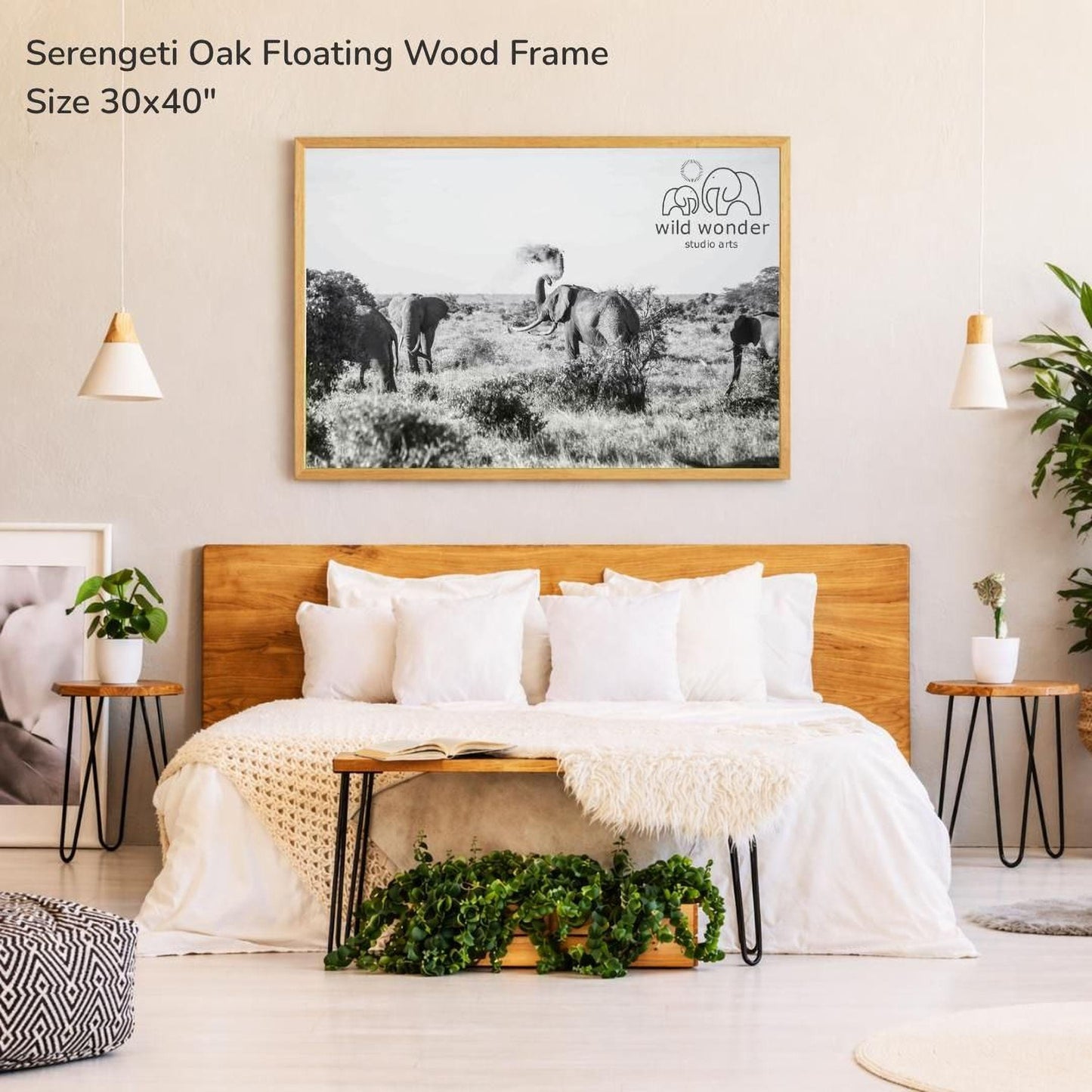 a bedroom with a large framed photograph of elephants hanging on the wall above a bed with white bedding.