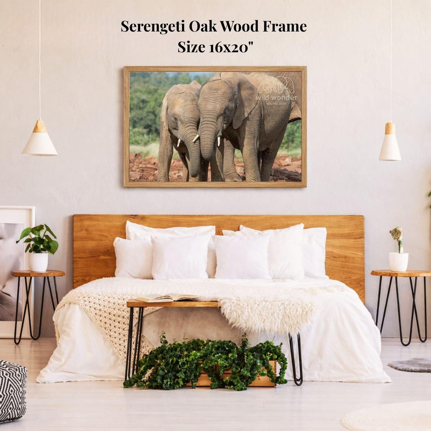 a serene bedroom scene with a large framed photograph of two elephants standing close together on a wooden frame above a bed with white bedding.