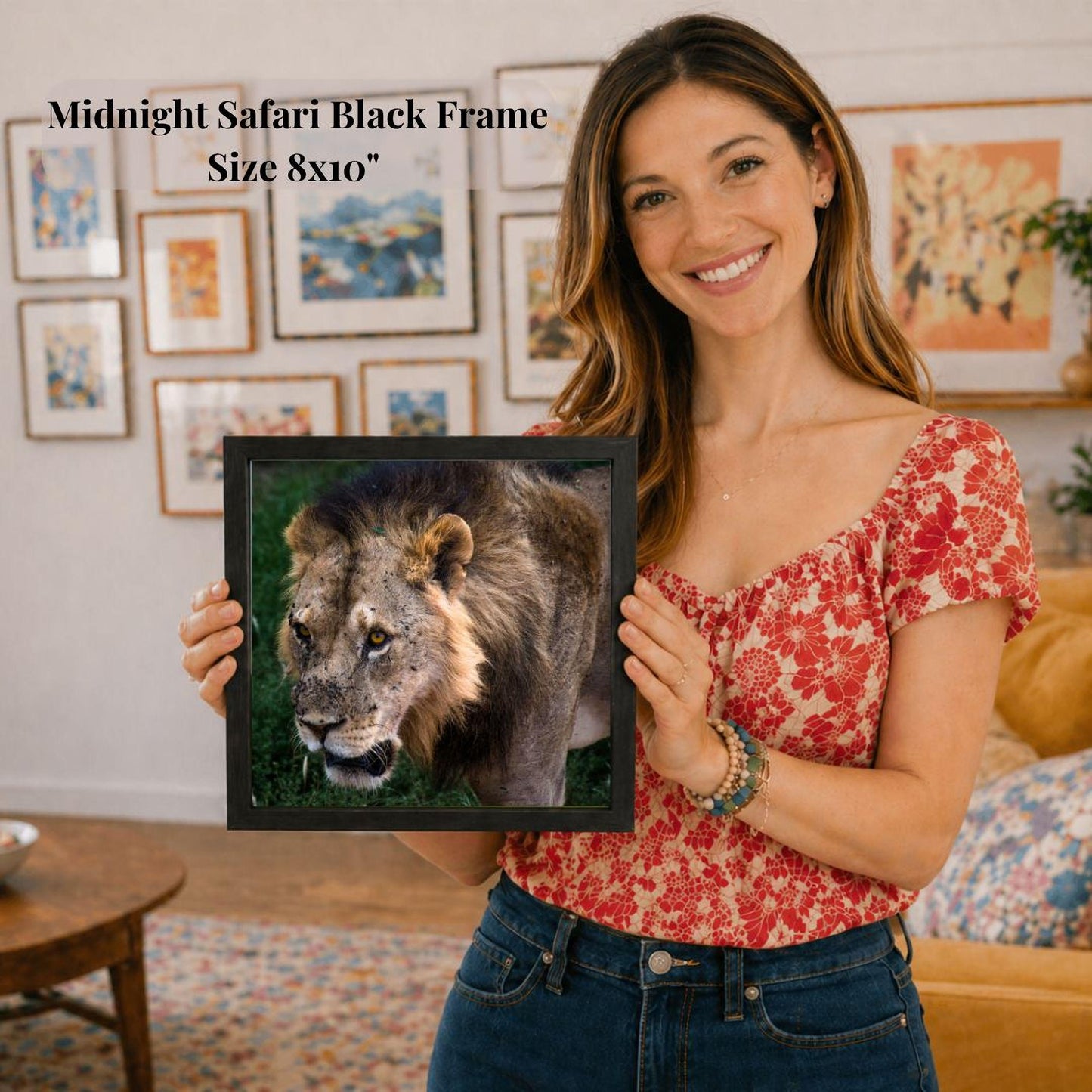 A woman is holding a framed picture of a lion in front of her, smiling and posing for the camera.