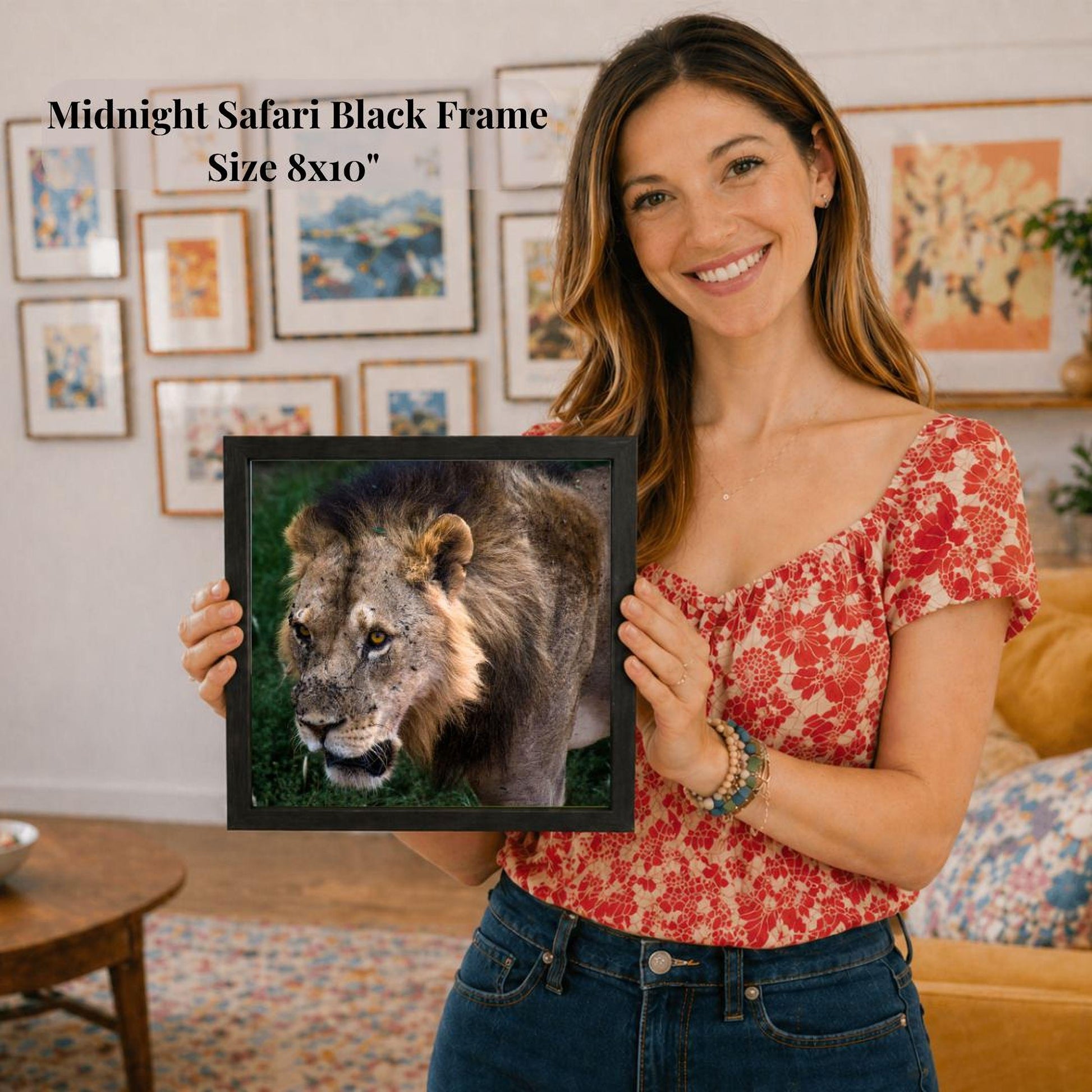A woman is holding a framed picture of a lion in front of her, smiling and posing for the camera.