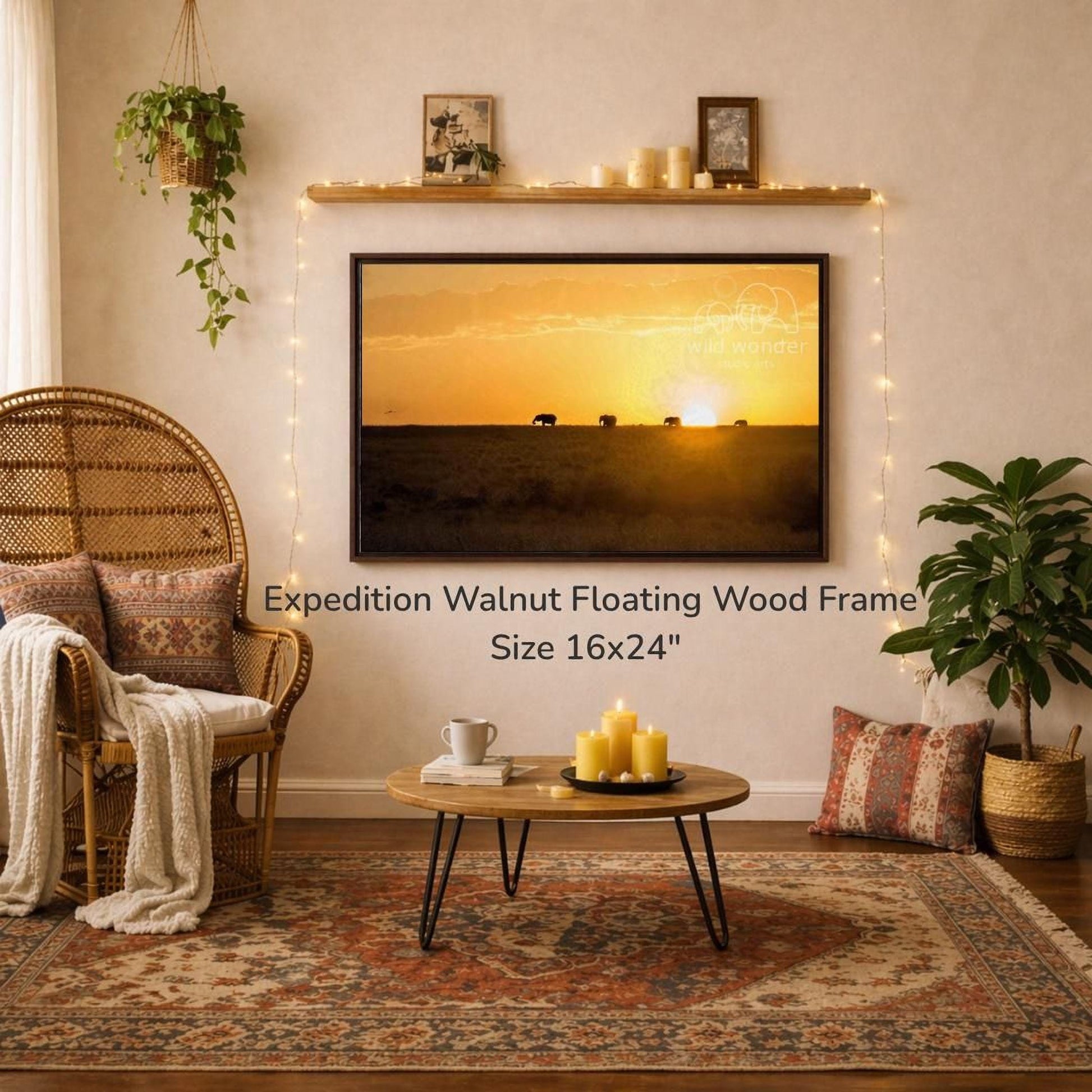 a living room with a large 16x24" walnut floating wood frame hanging on the wall, a coffee table in front of it, and a wicker chair. The room is decorated with plants, candles, and a rug, creating a cozy and inviting atmosphere.