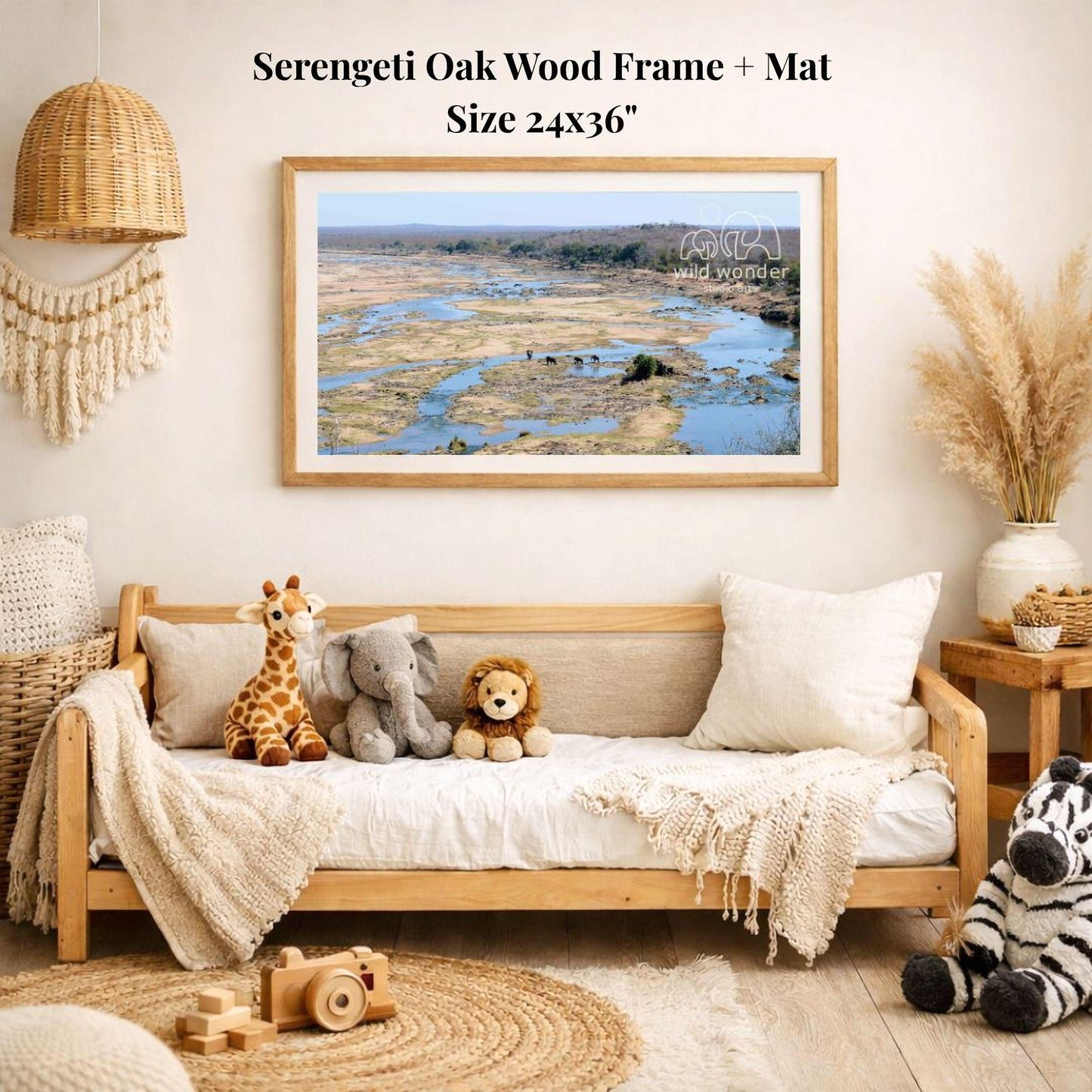 a serene indoor setting with a wooden frame and mat hanging on the wall, displaying a landscape photograph of a river and forest. The room is decorated with various items, including a sofa with stuffed animals, a woven basket, and a potted plant.