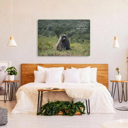 a bedroom with a large metal print of a bear sitting in the grass on the wall. The bedroom has a wooden headboard and a white bedding set. There are also two potted plants and a small table in the room.