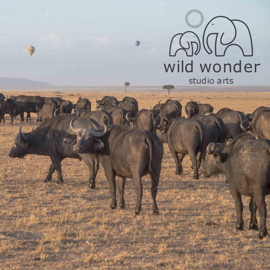 A herd of wild buffalo grazing in a dry grassland, with hot air balloons floating in the sky above.